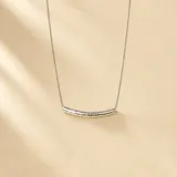 Collar de plata 925 con cadena fina de eslabones y un dije tubular curvo con textura cuadriculada.