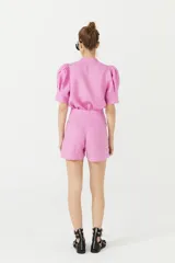 Short de lino color rosa con cintura alta, pinzas delanteras, bolsillos laterales y cierre frontal con gancho metálico.