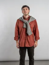 Camisa de corte regular, color terracota, de manga larga y diseño liso, con cuello camisero y cierre frontal de botones.