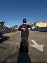 Remera negra de manga corta y corte oversize, con estampa en la espalda que incluye el logo 'IS' en rojo y texto blanco con la leyenda 'ittaidepartament NOT A BRAND, MOVEMENT 04D'.