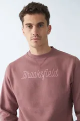 Buzo de felpa color rosa con logo estampado, cuello redondo, mangas largas y puños.