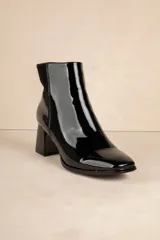 Botas de caña baja color negro, de símil cuero con punta redonda, cierre lateral, taco cuadrado y recorte en gamuza en la parte trasera.