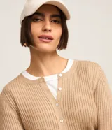 Cardigan corto color tostado de punto con textura acanalada, cuello redondo, manga larga y cierre frontal con botones.