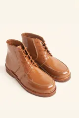 Bota acordonada de cuero vacuno con acabado charol color suela, con suela de goma tipo crepe y costuras reforzadas.