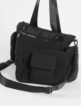 Cartera tipo bolso color beige con detalles en negro, confeccionada en nylon. Presenta múltiples compartimentos externos, incluyendo bolsillos laterales removibles, cierre superior y correas de hombro resistentes.