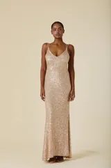 Vestido largo de fiesta completamente cubierto de lentejuelas doradas, con escote en V, tirantes finos dobles y corte ajustado que se ensancha ligeramente hacia el ruedo.