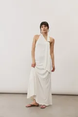 Vestido largo negro de corte al cuerpo con cuello halter y detalle de hebilla metálica dorada en el hombro con tira drapeada.