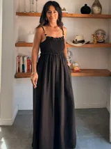 Mono largo negro de crepé con escote smock fruncido en el busto y tirantes finos con detalles de cuentas. La parte inferior es de corte amplio y fluido.