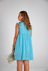 Vestido corto color fucsia, con escote en V profundo y mangas cortas tipo volado. Presenta un diseño con textura de bordado inglés o perforado y un corte imperio con frunce que da volumen a la falda.