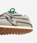 Championes de estilo retro inspirados en botines de fútbol, con capellada de poliuretano en color beige y detalles en azul marino. Presentan suela tractorada color caramelo, refuerzo en el talón y cordones combinados en gris y verde.