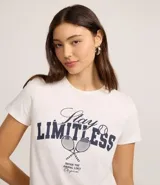 Remera de algodón color blanco con estampa frontal en azul marino que dice "Stay LIMITLESS" y un dibujo de dos raquetas de tenis cruzadas con una pelota.