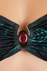 Top de bikini estilo bandeau con frunces laterales y detalle de piedra central. Presenta un estampado orgánico de líneas onduladas en tonos turquesa y marrón.