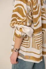 Camisa de manga larga de corte holgado, color blanco con estampado abstracto y floral en tonos ocre y azul.