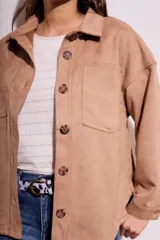 Sobrecamisa negra de estilo shacket, confeccionada en tejido de gamuza sintética. Presenta cuello camisero, cierre frontal de botones y dos bolsillos de parche con solapa en el pecho. El calce es oversize y las mangas son largas.