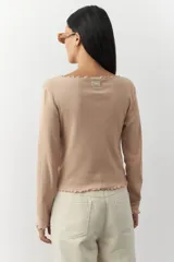 Remera blanca de manga larga con cuello redondo y costuras a la vista.