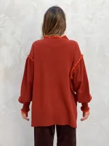 Sweater de lana color rosado, con cuello alto y detalles de volados en los hombros y puños.