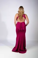 Vestido largo de fiesta color fucsia, con escote halter y corte sirena que se ajusta al cuerpo hasta la rodilla y se ensancha hacia el ruedo.