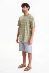 Remera oversize de manga corta confeccionada en 100% algodón, con diseño a rayas horizontales en tonos verde y blanco.