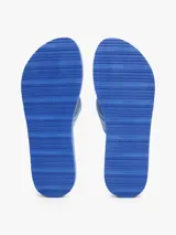 Ojotas de mujer color azul vibrante con suela de EVA de dos capas, separadas por una fina línea blanca. Las tiras son de tejido trenzado en tonos de azul claro y llevan la inscripción tonal "Tommy Hilfiger".
