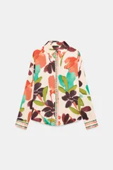 Camisa satinada de manga larga con cuello solapa y cierre frontal con botones, con un colorido estampado floral de estilo acuarela sobre fondo beige.