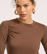 Blusa ajustada de manga larga color marrón, con cuello redondo y fruncido en los hombros y laterales.