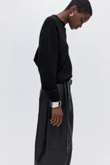 Buzo negro de tejido suave con lana, cuello redondo acanalado, hombros caídos y mangas largas. Puños y bajo en punto acanalado.