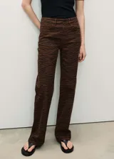 Pantalón de jean con diseño recto y tiro alto, confeccionado en algodón con estampado animal print de cebra en tonos marrones. Cuenta con cierre frontal de cremallera y botón, trabillas para cinturón y cinco bolsillos clásicos.