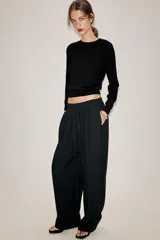 Pantalón fluido de tiro medio, confeccionado en mezcla de modal, con cintura elástica ajustable mediante cordones. Presenta pinzas en el delantero, bolsillos laterales ocultos y bajo ajustable con trabilla y botón a presión.