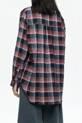 Camisa de corte recto y largo medio, confeccionada en tejido de algodón con textura. Presenta un diseño de cuadros en tonos rojo, negro y azul, cuello camisero, cierre frontal con botones, manga larga con puños abotonados y bolsillo de plastrón en el pecho.