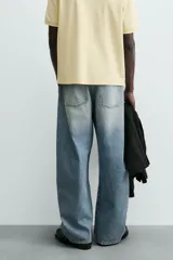 Jeans de hombre, corte balloon fit, tiro medio, confeccionados en denim rígido de algodón. Presentan un efecto lavado con un marcado degradado vertical, cinco bolsillos y cierre frontal con cremallera y botón.