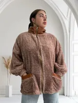 Campera de abrigo color marrón claro, estilo teddy, con cierre frontal y bolsillos con ribete de cuero sintético.