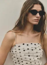 Top de tirantes finos color blanco con estampado de lunares negros, diseño fruncido y escote recto.