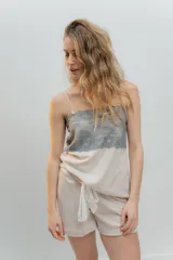Pijama de dos piezas, compuesto por una musculosa blanca con detalle de puntilla negra elástica en el escote y un short blanco con elástico y lazo negro en la cintura.