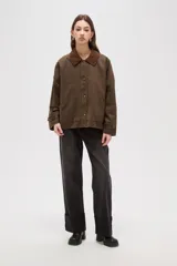 Campera de estilo encerado color marrón, con cuello de pana en tono contrastante, cierre frontal con cremallera y botones a presión, y bolsillos laterales. Presenta un diseño holgado con forro interior a cuadros.