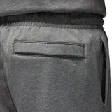 Pantalón de jogging Nike Jordan, confeccionado en tejido fleece gris melange. Presenta cintura elástica con cordón ajustable, bolsillos laterales y puños elásticos en los tobillos. Incluye un pequeño parche con el logo Jumpman en la pierna izquierda.