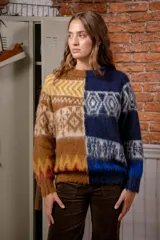 Sweater de punto con diseño bicolor, dividido verticalmente en tonos marrones y amarillos en un lado, y tonos azules en el otro. Presenta un patrón geométrico y de grecas en toda la prenda, con cuello redondo y puños acanalados.