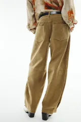 Pantalón de piel color tostado, tiro medio con cierre frontal de cremallera y botón, bolsillos delanteros y traseros, y bajo con acabado de pliegues.