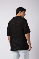 Camisa de manga corta tejida en algodón con diseño calado, cuello tipo bowling y cierre frontal con botones al tono.