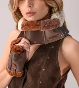 Cuello de cuero con interior de piel sintética, diseñado con paneles en tonos marrones y crema. Presenta detalles de remaches metálicos y una etiqueta de marca grabada.