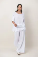 Blusa de lino color blanco, de corte amplio, con escote redondo, mangas cortas y detalle de guarda calada horizontal en la parte inferior.