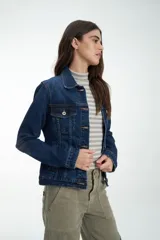 Campera de jean azul con cuello clásico, bolsillos frontales y cierre con botones metálicos.