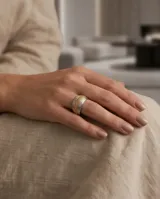 Anillo de acero quirúrgico de diseño ancho y abombado, que combina bandas plateadas lisas con una franja central dorada de textura granulada.