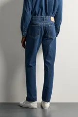 Jeans regular fit de tiro medio, confeccionados en denim de algodón azul oscuro con efecto lavado. Presenta diseño clásico de cinco bolsillos, pierna recta y cierre frontal con cremallera y botón.