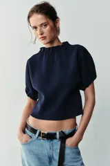Top de punto color azul marino, con cuello redondo y mangas cortas abullonadas con acabados elásticos fruncidos.
