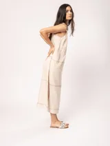 Vestido largo color crudo de lino, con silueta recta, escote en V, breteles anchos, detalle de elástico en la espalda y tajos laterales.