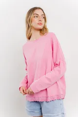 Remera rosa de algodón con mangas largas y ruedo con detalle de puntilla calada.