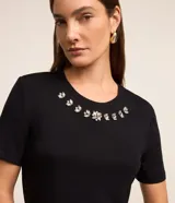 Blusa de manga corta color rojo, confeccionada en viscosa con elastano. Presenta cuello redondo decorado con apliques de cristales en forma de flores.