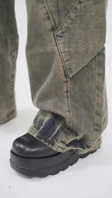 Pantalón de jean color marrón con efecto gastado, corte recto y diseño con paneles geométricos.