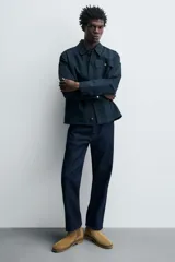 Bota estilo Chelsea de hombre, color marrón, fabricada en piel con acabado serraje (gamuza). Presenta elásticos laterales oscuros y suela de goma a tono con tacón bajo.