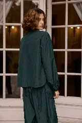 Camisa de nylon color verde oscuro, de corte holgado, con mangas largas abullonadas y puños elásticos.